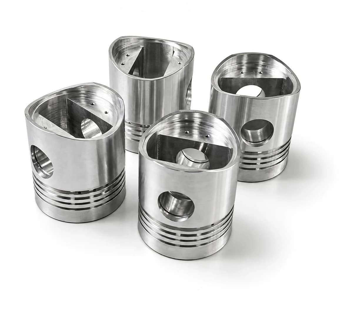 Four precision-machined metal components arranged on a neutral background.